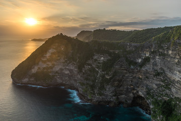 Fototapeta na wymiar Time exposure of the beautiful view at sunset over the cliffs and Pura Gunung Cemeng temple seen from Pererenan Sunset Point on Nusa Penida, Bali Indonesia (23.05.2018)
