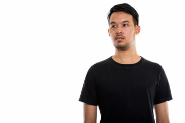 Fototapeta premium Studio shot of young Asian man thinking while looking at distanc