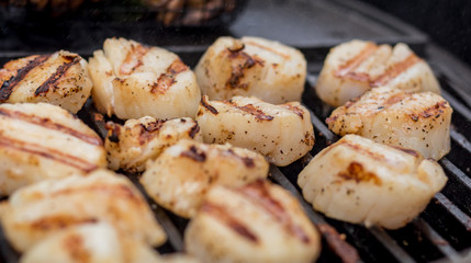 Delicious sizzling sea scallops grilling on a charcoal grill