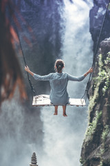 Beautiful woman swings near waterfall in the jungle of Bali island, Indonesia.