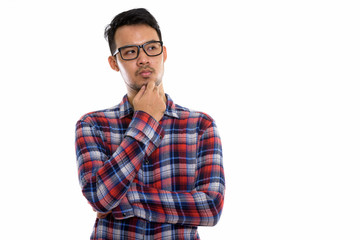 Studio shot of young Asian man thinking while wearing eyeglasses