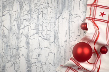 Christmas background with napkins, red baubles and ribbon on rustic wood, text