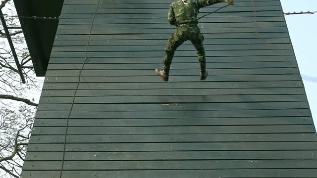 Slow motion of soldiers practice abseiling down a wooden platform. Group of chinese soldiers abseiling down fast. Anti terrorist training.