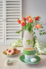 Springtime greeting card design with bunch of red tulips, espresso in green cup with white dots and cookies