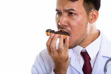Close up of young Asian man doctor eating donut and thinking