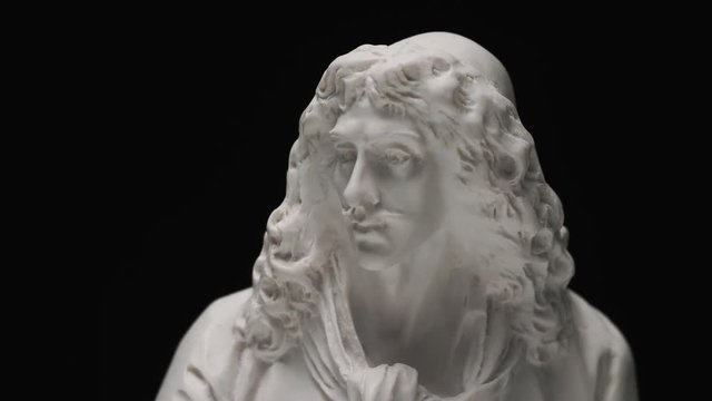 Old sculpture of Moliere made out of marble. Camera panning vertically revealing the sculpture.