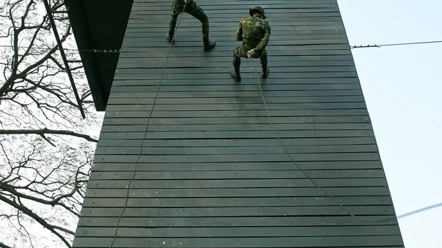 Slow motion of soldiers practice abseiling down a wooden platform. Group of chinese soldiers abseiling down fast. Anti terrorist training.