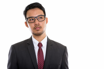 Studio shot of young Asian businessman wearing eyeglasses while 