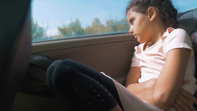 sad girl bored sitting in the car in the back seat motion travel . little girl bored in the car. concept kid car long lifestyle journey