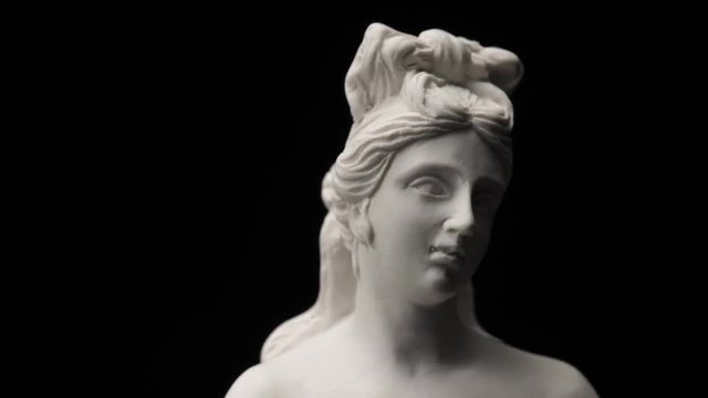 Ancient roman era white marble statue of Venus rotating and showing every angles. Closeup shot  with black background.