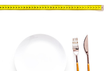 Diet for weight loss concept. Proper nutrition. Medical starvation. Empty plate with fork and knife near measuring tape on white background top view mockup