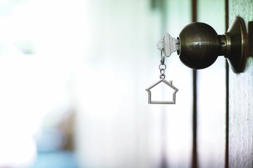 Home key with house keychain in keyhole, property concept