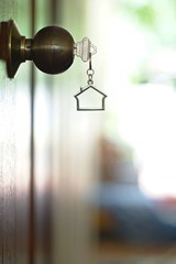 Home key with house keychain in keyhole, property concept