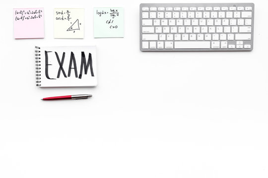 Exam concept. Lettering Exam in notebook on student's work desk on white backgrond top view copy space