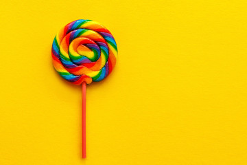 multicolored lollipop on yellow background, top view. flat lay, copy space