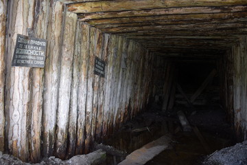 Fototapeta na wymiar Abandoned mine entrance with a couple of safety warnings in Russian on the wall