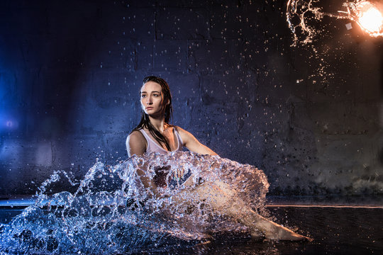 Girl with long hair during photoshoot with water in photo studio