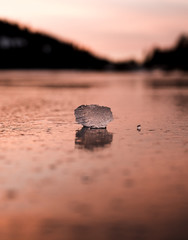 A lone piece of ice catches the last sunlight on a frozen alpine lake