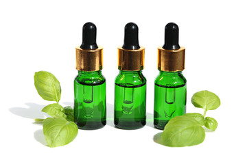 Basil Oil. natural essential oil Basil set of green glass bottles and basil leaves on a white background
