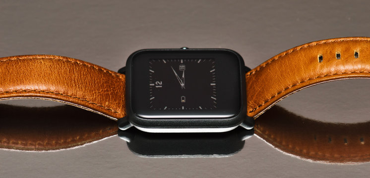 Smart watch with a brown leather strap on a reflective background