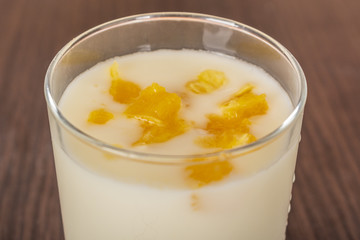 yogurt with orange jam in a glass cup on a rustic wooden table on a brick wall background