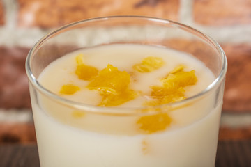 yogurt with orange jam in a glass cup on a rustic wooden table on a brick wall background