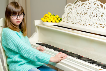 Girl schoolgirl near the piano on which lies a bouquet of flower