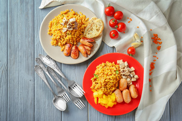 Plates with tasty lentils, sausages and vegetables on wooden background