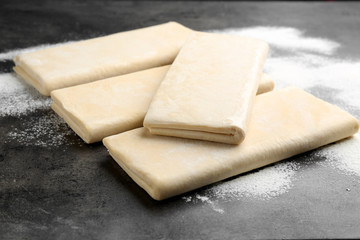 Raw wheat dough and flour on grey table