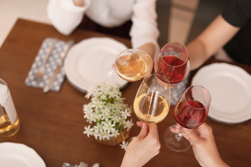 Young people with glasses of delicious wine at table