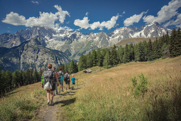 Fototapeta na wymiar Group of People with backpacks walking on a mountain path. A beautiful sunny day to trekking with family and friends climbing to the mountains for an excursion in nature. Enjoying a summer day.