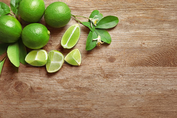 Composition with fresh ripe limes on wooden background, top view