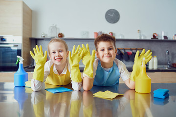 Smiling children do the cleaning in the kitchen.