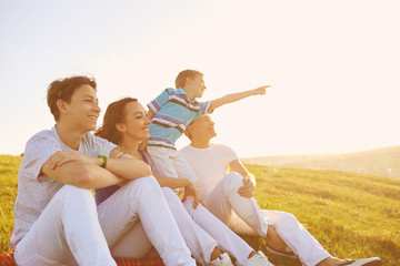 Happy family sitting on nature in summer.