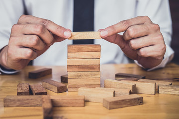 Risk To Make Business Growth Concept With Wooden Blocks, hand of man has piling up and stacking a...