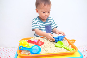 Cute little Asian 18 months / 1 year old toddler boy playing with kinetic sand at home ,Fine motor skills development, Montessori education, Creative play for kids concept - Selective focus at hands