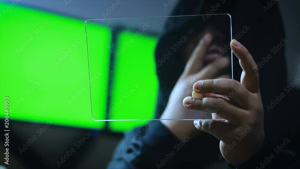 Poster hacker using clear tablet with green screen monitor background