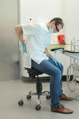 Dentist with lower back pain at work in his office in his office