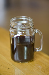 A half full dark coffee in a mason jar
