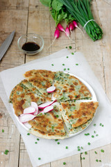 Homemade appetizing scallion pancakes with a bunch of green onions and radishes. Rustic style.
