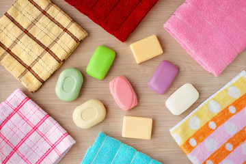 Obraz na płótnie Canvas Soap surrounded by bath towels. Multi-colored soap and bath towels on a wooden background. View from above. Hygiene items.