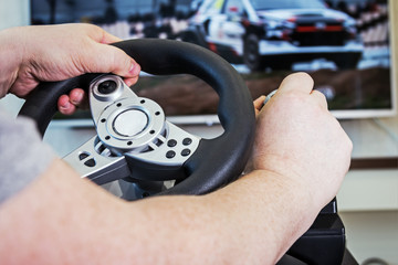 hands holding the steering wheel of the game console. Modern game technologies