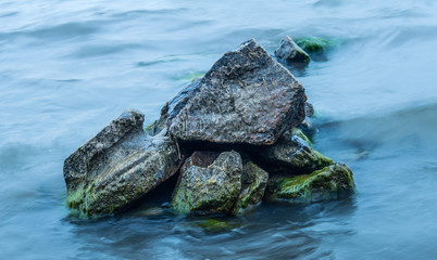 Fototapeta na wymiar Wet stones, covered with green mud