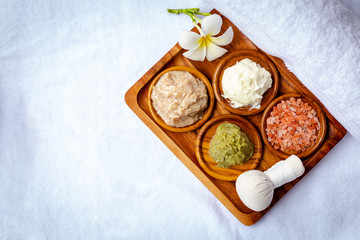Spa stuff and beautiful flower on the beautiful wooden tray and vintage bamboo mat background with sunlight. The stuff are salt scrub, moisturizer cream, herbal ball and nice smell candle. copy space