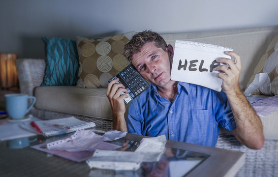 young worried in stress man at home calculating month tax expenses with calculator accounting payments sad and depressed asking for help