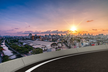 Obraz premium empty asphalt road with cityscape in sunset background