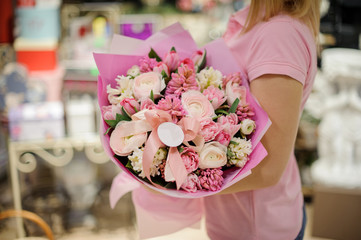 Woman holding tender pink flower composition consisting of roses, ranunculus and other beautiful flowers