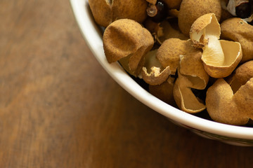 Longan peel in a bowl on wood background