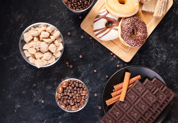 Different types of deserts on a black wooden table in studio photo