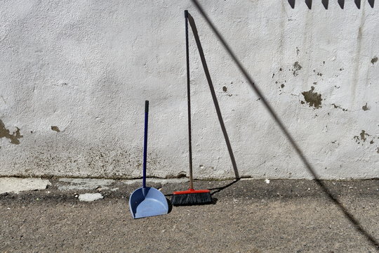 Balai et balayette appuy&eacute;s sur un mur blanc